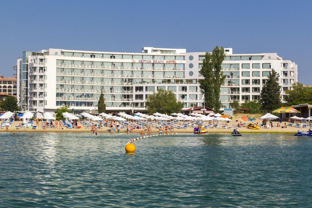 plaża z ludźmi i parasolami oraz duży budynek w obiekcie Hotel Neptun Beach w Słonecznym Brzegu