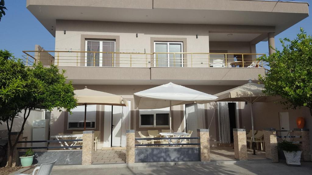 un edificio con tavoli e ombrelloni di fronte ad esso di Villa Roel 2 apartments nr 88 a Vlorë