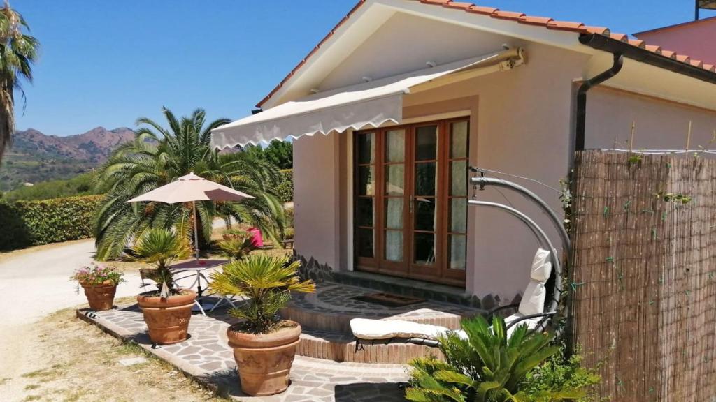 a small house with an umbrella and some plants at Villetta I Due Pini - ArgonautiVacanze in Capoliveri