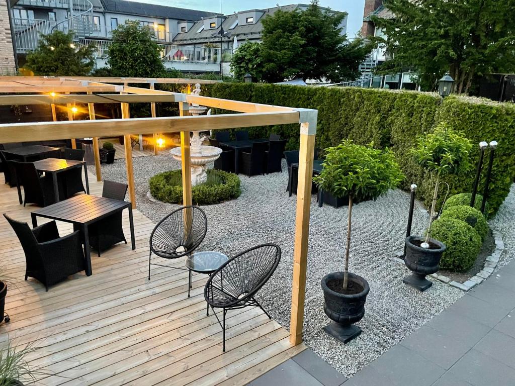 a wooden deck with chairs and tables in a garden at Hotell Dannegården in Trelleborg