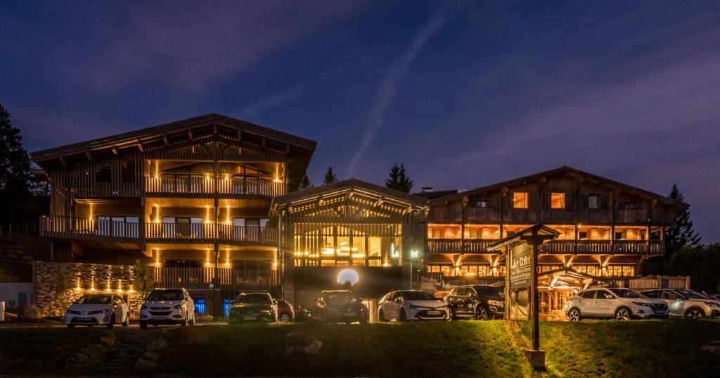 un bâtiment avec des voitures garées devant lui la nuit dans l'établissement Chalet Hotel Le Collet, à Xonrupt-Longemer