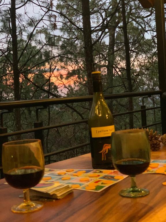 una botella de vino sentada en una mesa con dos copas en Cabañas San Marcos, en Mazamitla