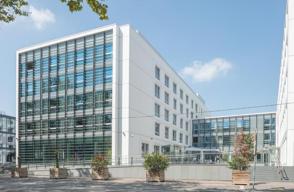 a large white office building with potted plants in front of it at Hotel Lyon-ouest in Lyon