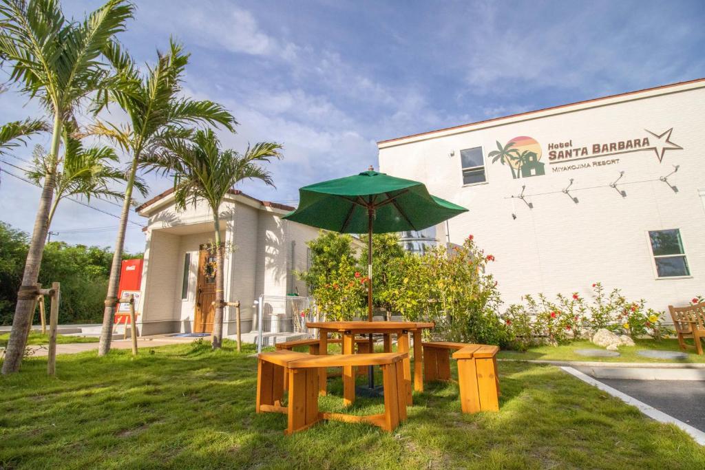 einem Picknicktisch mit einem Regenschirm vor einem Gebäude in der Unterkunft Hotel Santa Barbara Miyakojima Resort in Miyako-jima