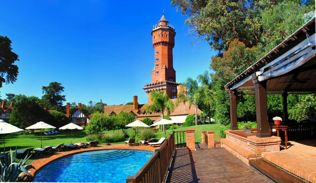 ein Gebäude mit einem Uhrturm und einem Pool in der Unterkunft Hotel L'Auberge in Punta del Este