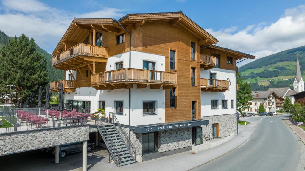 un grand bâtiment avec des balcons en bois dans une rue dans l'établissement Herz3 Hotel Bar Restaurant Trattoria, à Hollersbach im Pinzgau