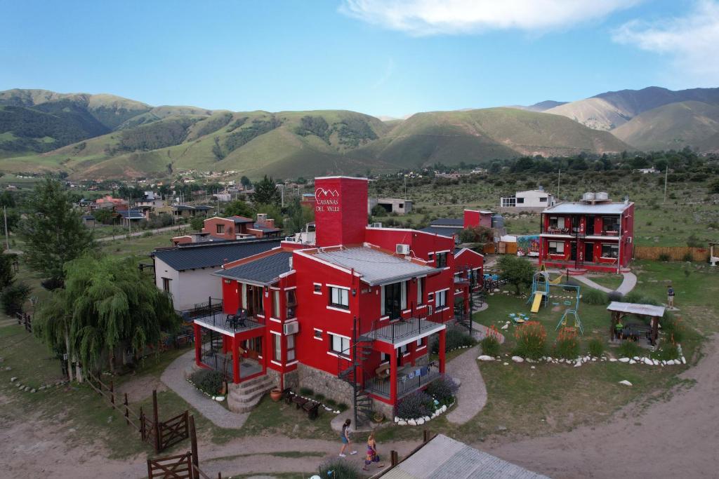 une vue aérienne sur une maison rouge avec des montagnes en arrière-plan dans l'établissement Apart del Valle, à Tafí del Valle