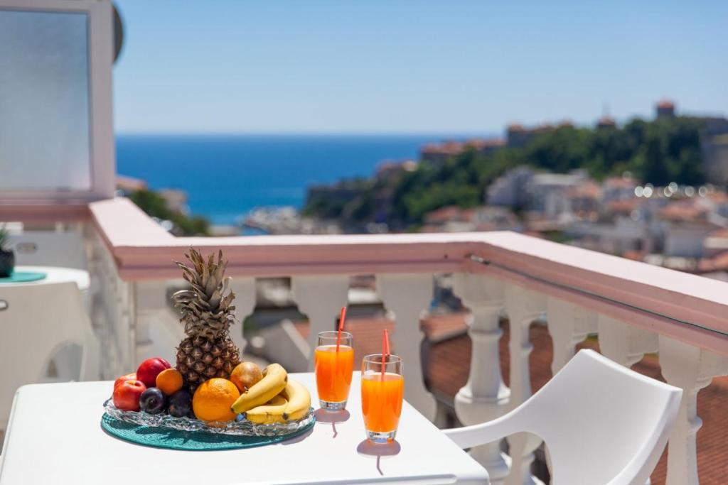 a plate of fruit and drinks on a table on a balcony at Castello Apartments in Ulcinj