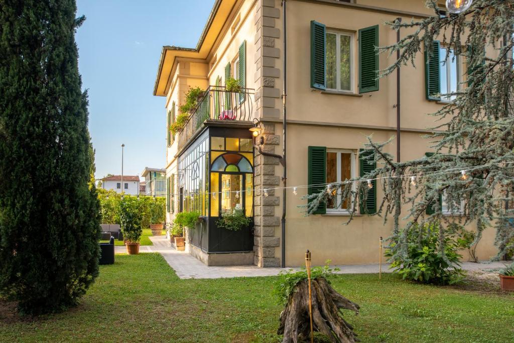 een gebouw met groene luiken en een tuin bij Villa Romantica Wellness & SPA in Lucca