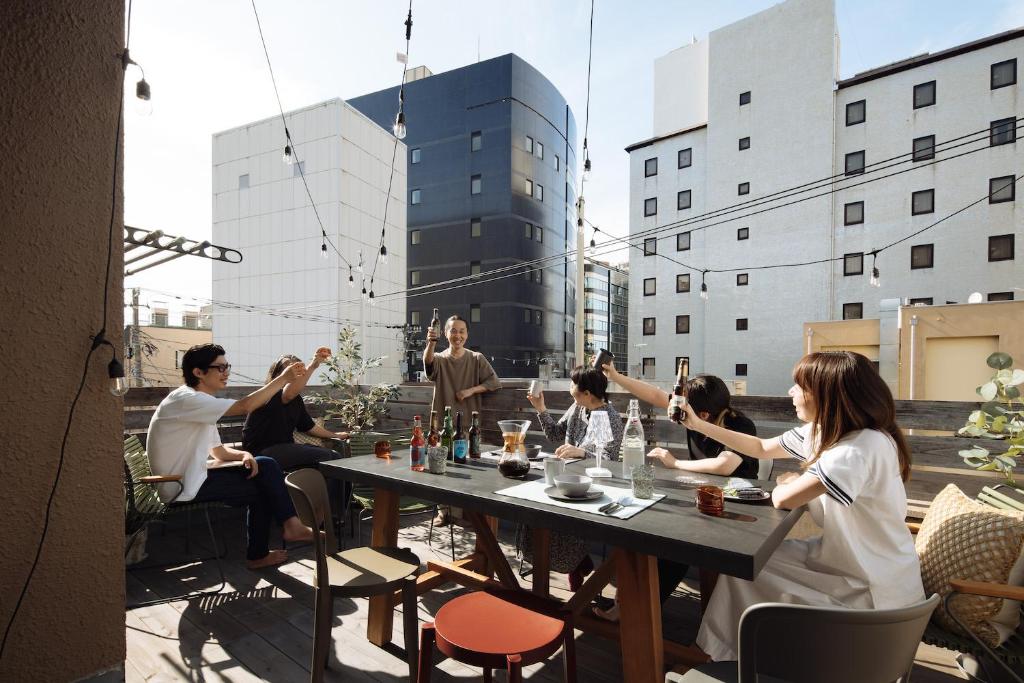 een groep mensen aan een tafel op een dak bij Good Neighbors in Kanazawa