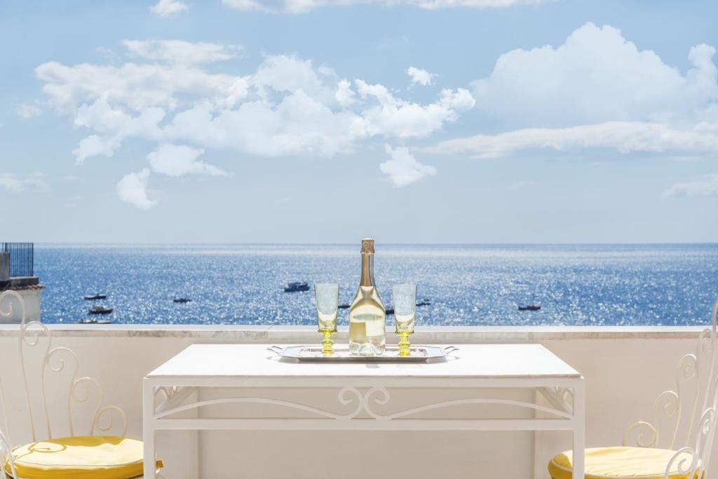 uma mesa branca com uma garrafa de vinho e copos em Villa Flavio Gioia em Positano