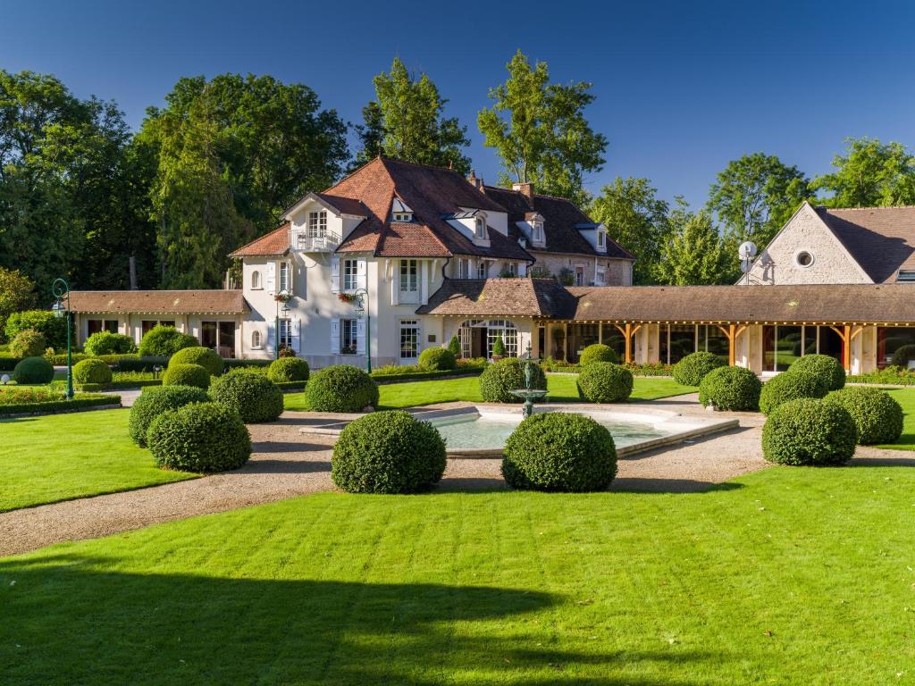 uma grande casa branca com um quintal com arbustos em Hostellerie De Levernois em Levernois