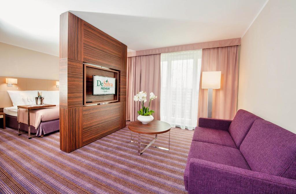 Habitación de hotel con sofá púrpura y cama en Hotel DeSilva Premium Opole, en Opole