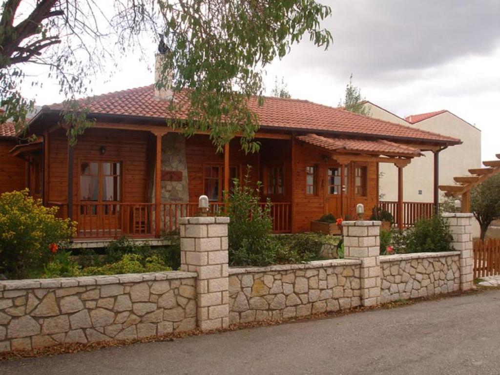 uma casa de madeira com uma cerca de pedra em frente em Xylino Chalet em Kalavrita