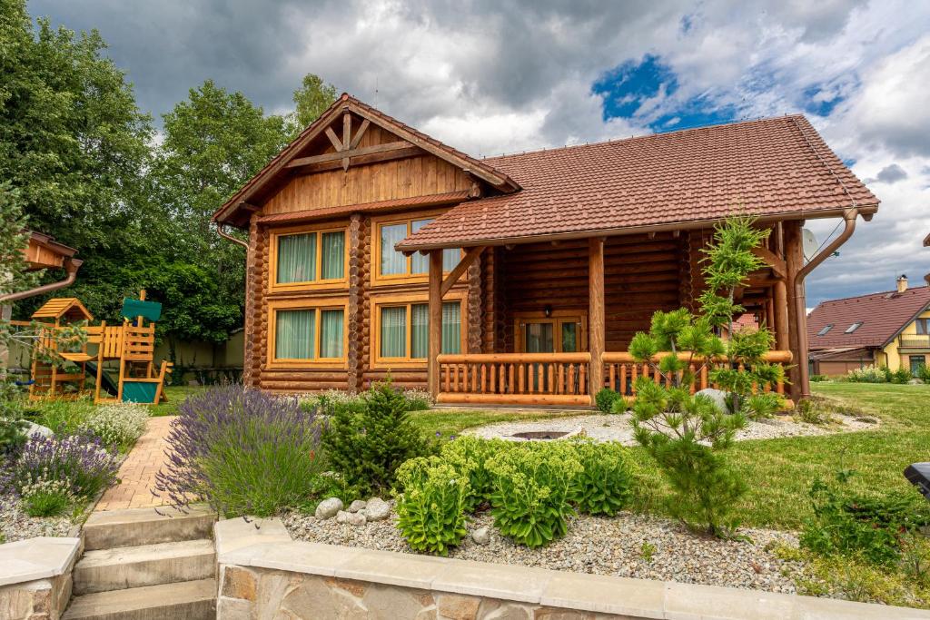 une cabane en rondins avec un jardin en face de celle-ci dans l'établissement Tatranský Zrub, à Nová Lesná