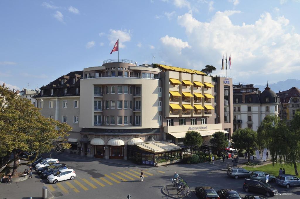 a large white building with cars parked in a parking lot at Studios Astra Hotel Vevey in Vevey