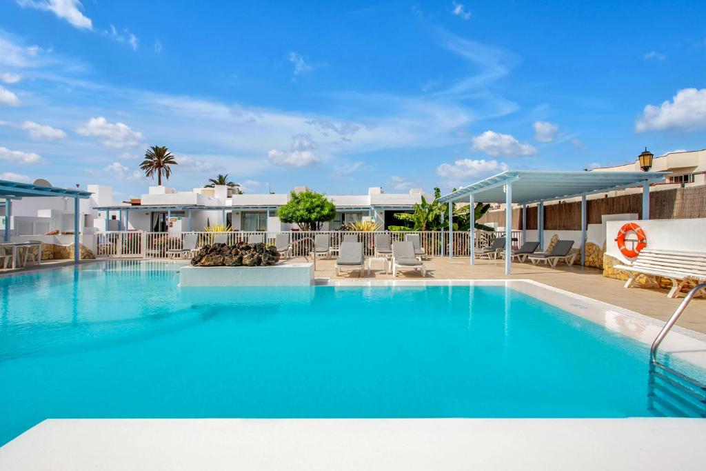 une grande piscine bleue avec des chaises et un bâtiment dans l'établissement Mar Azul Corralejo- Adults Only, à Corralejo