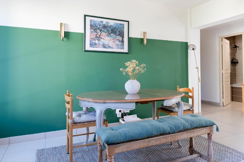 uma sala de jantar com uma mesa e uma parede verde em Appartement spacieux 1 chambre parking gratuit em Valence