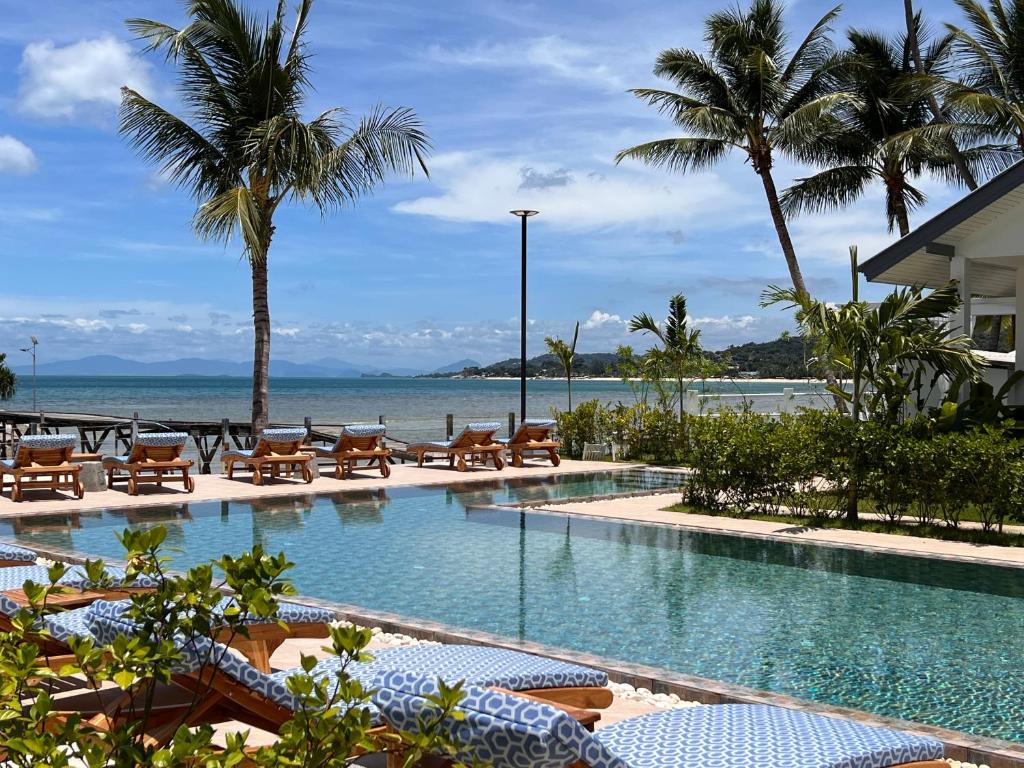 uma piscina com cadeiras e o oceano ao fundo em Pearl of Samui Resort em Lamai