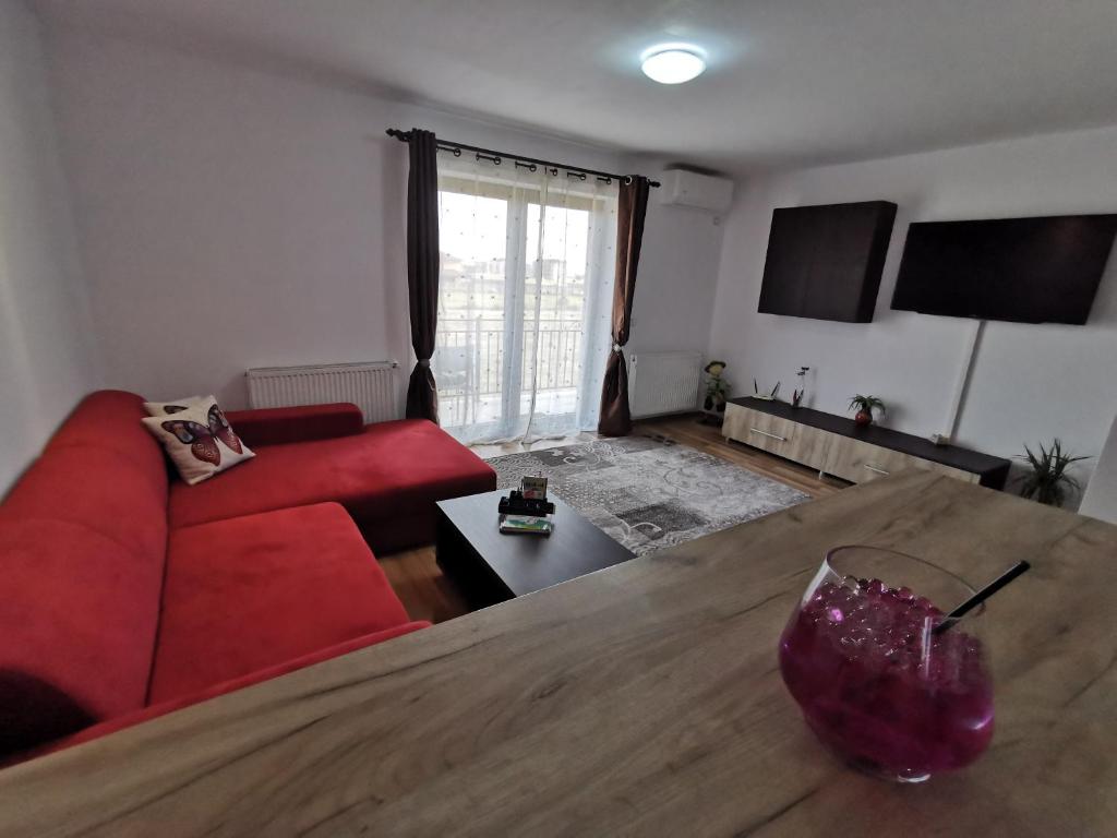 een woonkamer met een rode bank en een houten tafel bij Apartament Ovidiu in Giroc