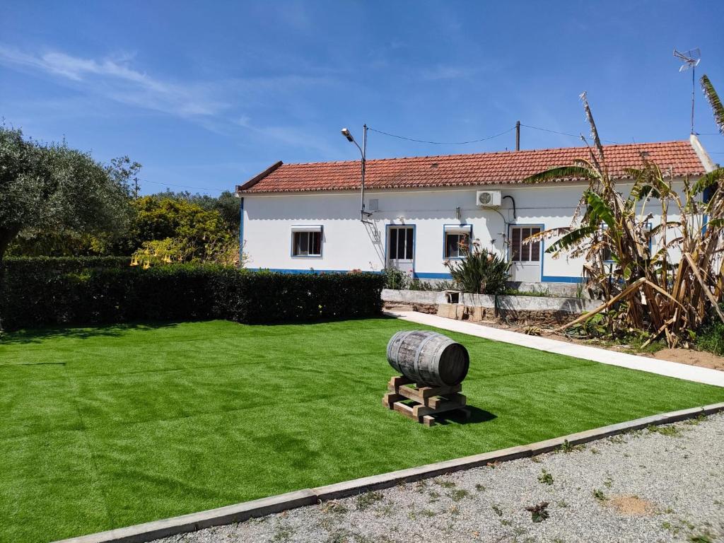 una casa con césped con un barril en el patio en Monte da Vinha Nova, en Santiago do Cacém