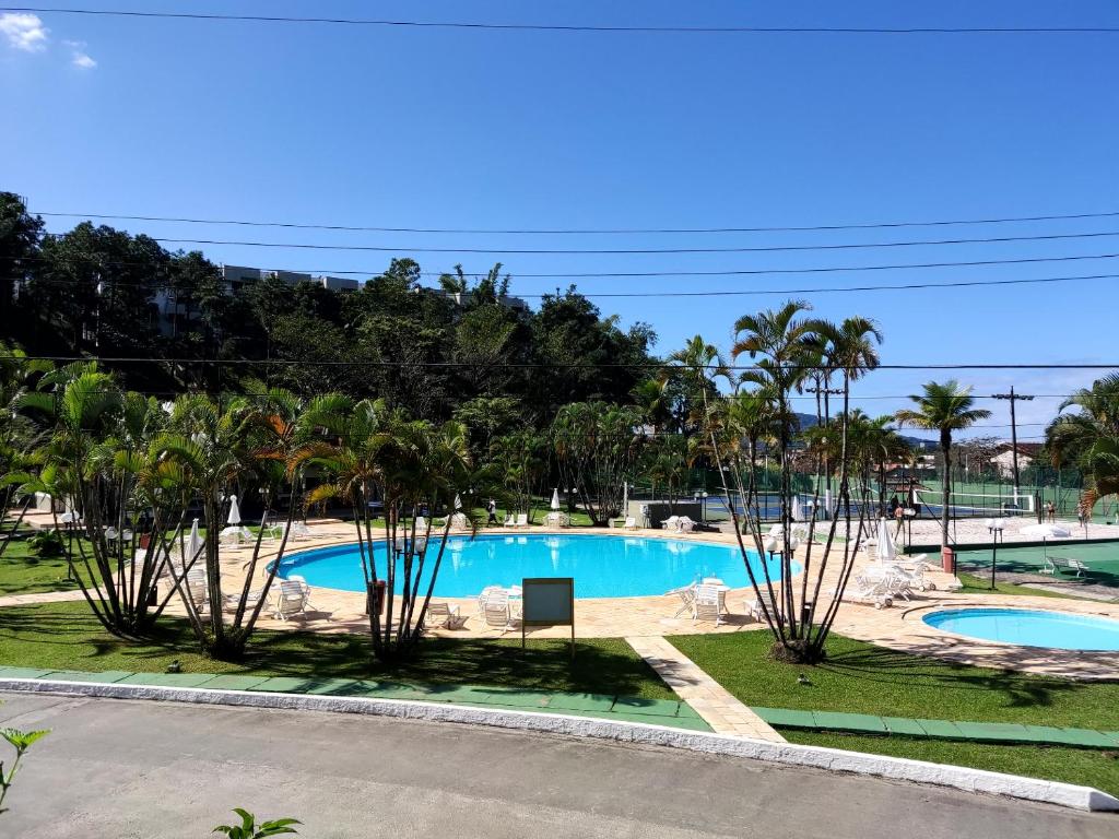 Apartamento até 10 pessoas na enseada Guarujá em condomínio clube praia piscinas salão jogos quadra futebol campo parquinho brinquedos Wi-fi Home office في غوارويا: اطلالة المسبح من شرفة المنتجع