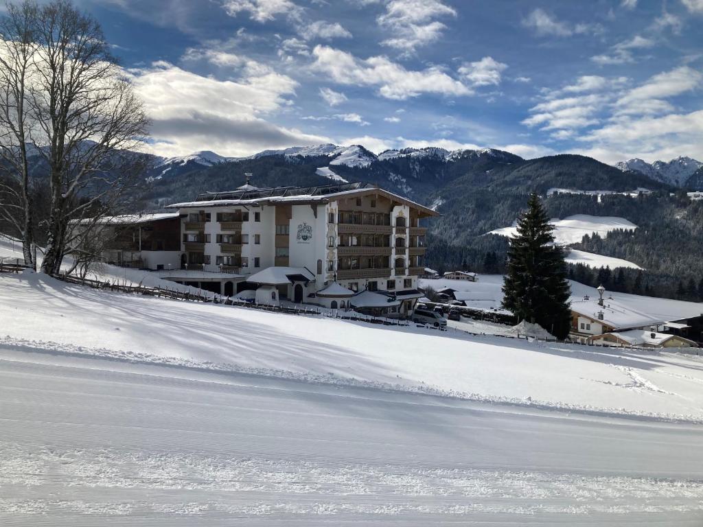 un edificio nella neve di fronte a una montagna di Hotel Silberberger - Wildschönau a Oberau