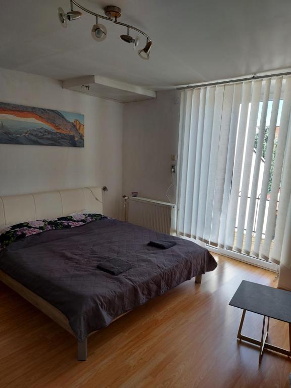 1 dormitorio con 1 cama grande y ventanas grandes en Picolo apartmany, en Levoča