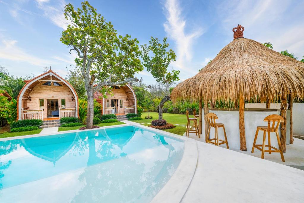 een huis met een zwembad en een rieten dak bij Uluwatu Desa in Uluwatu