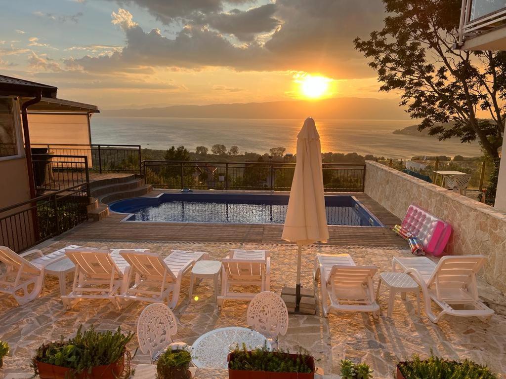 een zonsondergang boven een zwembad met stoelen en een parasol bij Villa Aurora in Ohrid