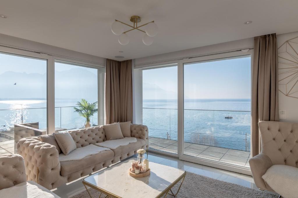 een woonkamer met een bank en een groot raam bij Sunset Home, Appartement de luxe front de lac in Veytaux