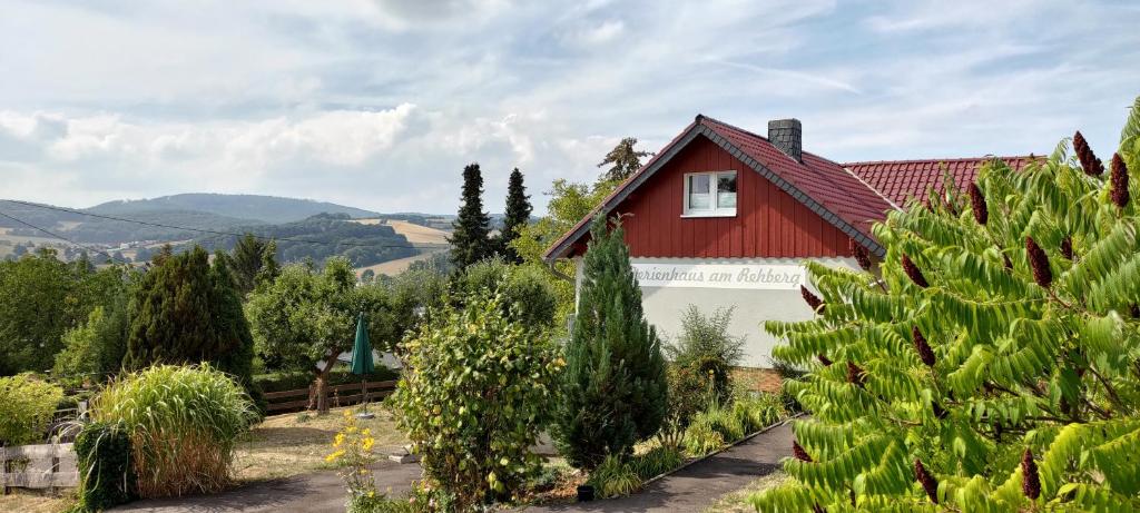 een rood huis met een rood dak en enkele bomen bij Ferienhaus am Rehberg in Eisenach