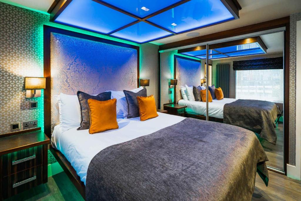 a hotel room with two beds and a mirror at Church Suites by The Cranleigh Boutique in Bowness-on-Windermere