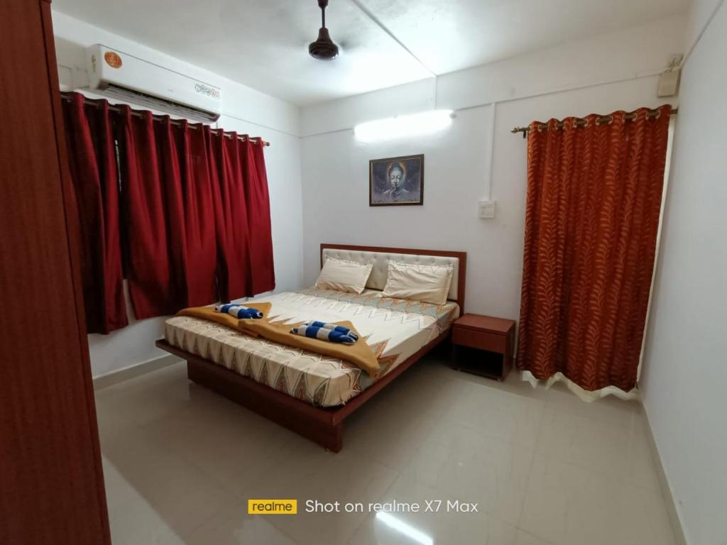 Schlafzimmer mit einem Bett und roten Vorhängen in der Unterkunft Palolem Sunrise Apartment in Palolem