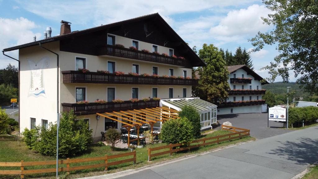 ein großes weißes Gebäude mit schwarzem Dach in der Unterkunft Hotel-Landgasthof Ploss in Schönwald