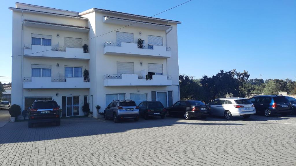 un edificio bianco con auto parcheggiate in un parcheggio di Casa Talika a Fátima