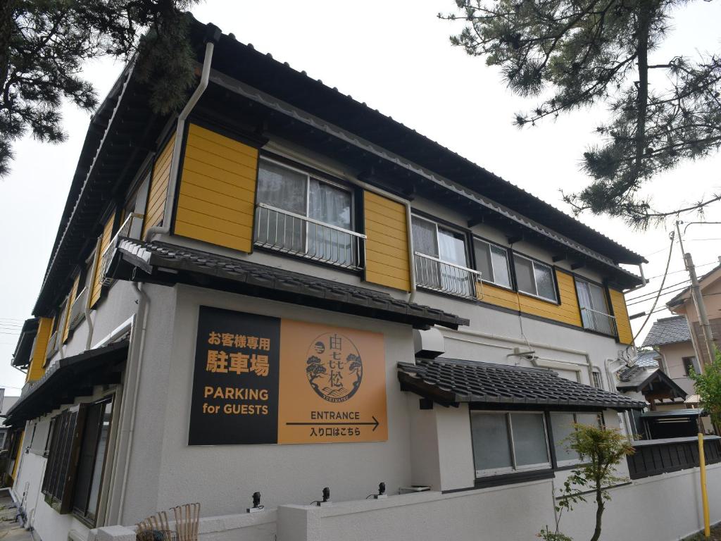 un bâtiment jaune et blanc avec un panneau sur lequel figure un panneau dans l'établissement 由㐂松, à Nishiizu