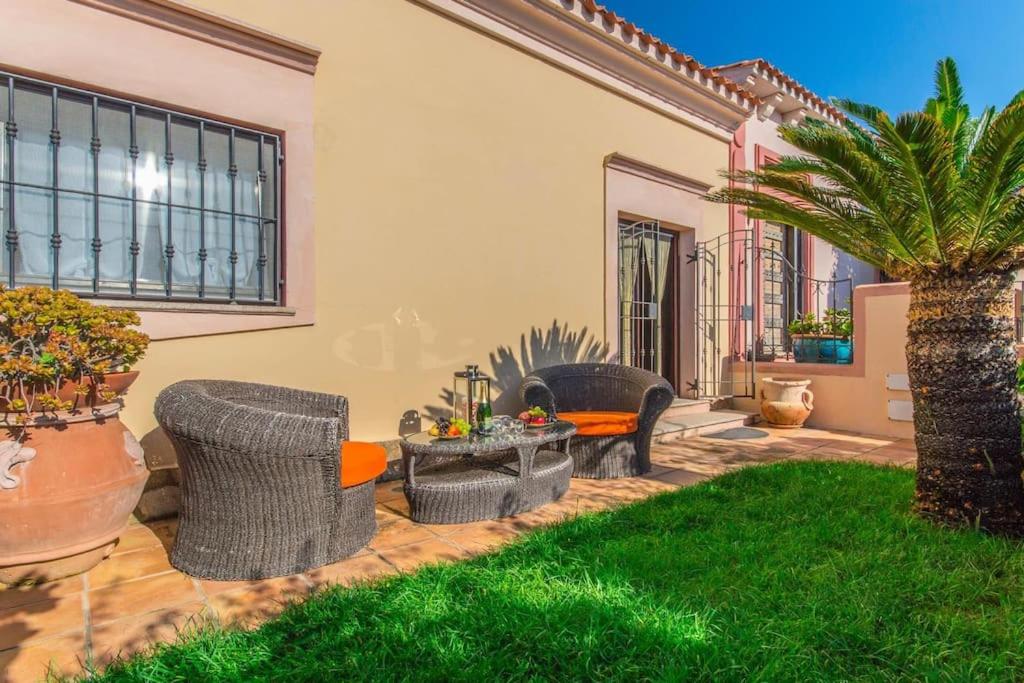 a patio with chairs and a table and a palm tree at Sardinia Home in Palau