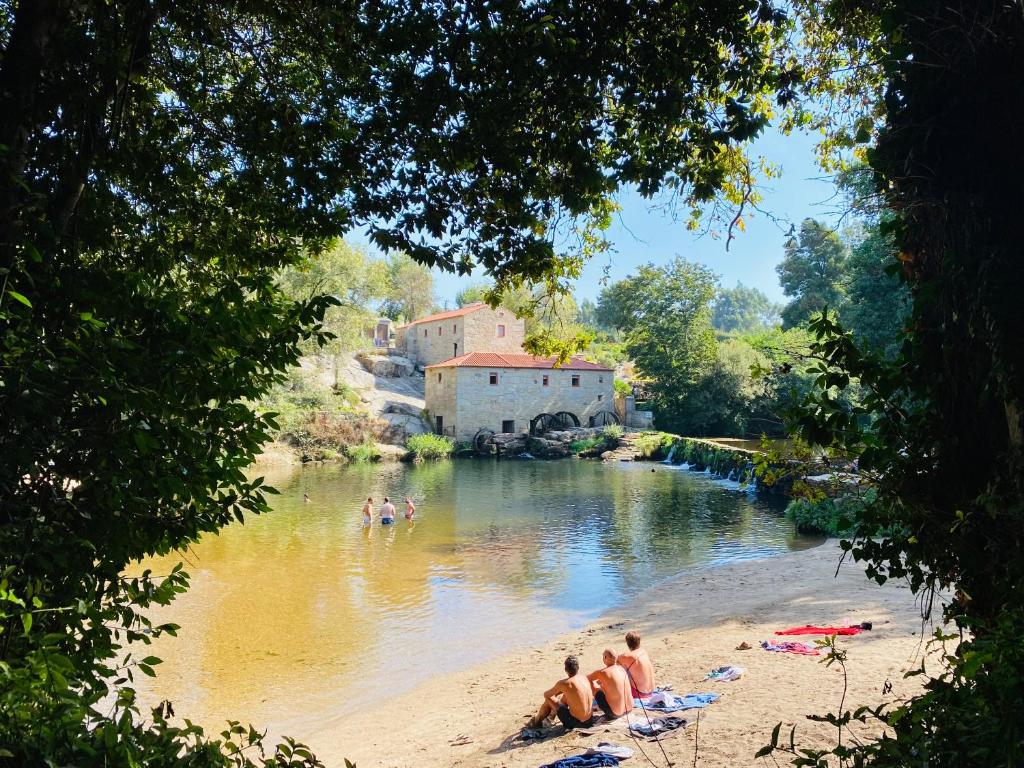 un groupe de personnes assises sur la plage à côté d'une rivière dans l'établissement Azenha do Tio Luís, à Caminha