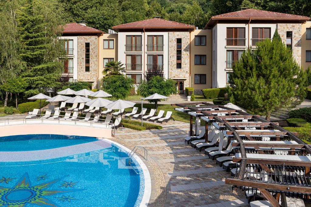 Pirin Park Hotel في ساندانسكي: منتجع فيه مسبح وكراسي ومبنى