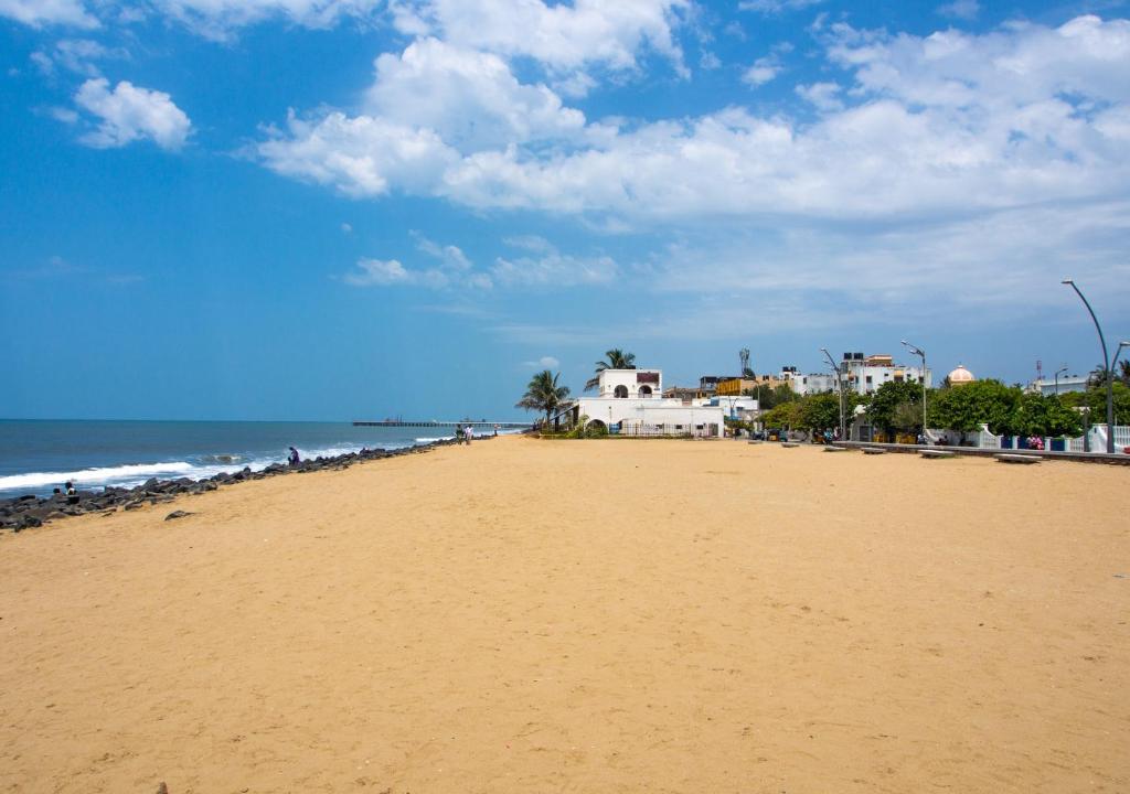 uma praia de areia com casas e o oceano em La Maison Pondichéry em Pondicherry