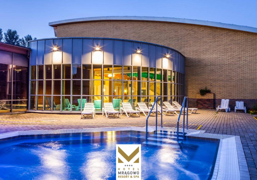 a building with a swimming pool in front of a building at Hotel Mrągowo Resort&Spa in Mrągowo