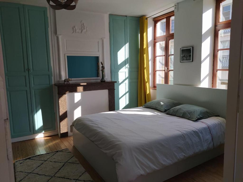 a bedroom with a bed and a tv and windows at Le Godefroy de Bouillon in Boulogne-sur-Mer