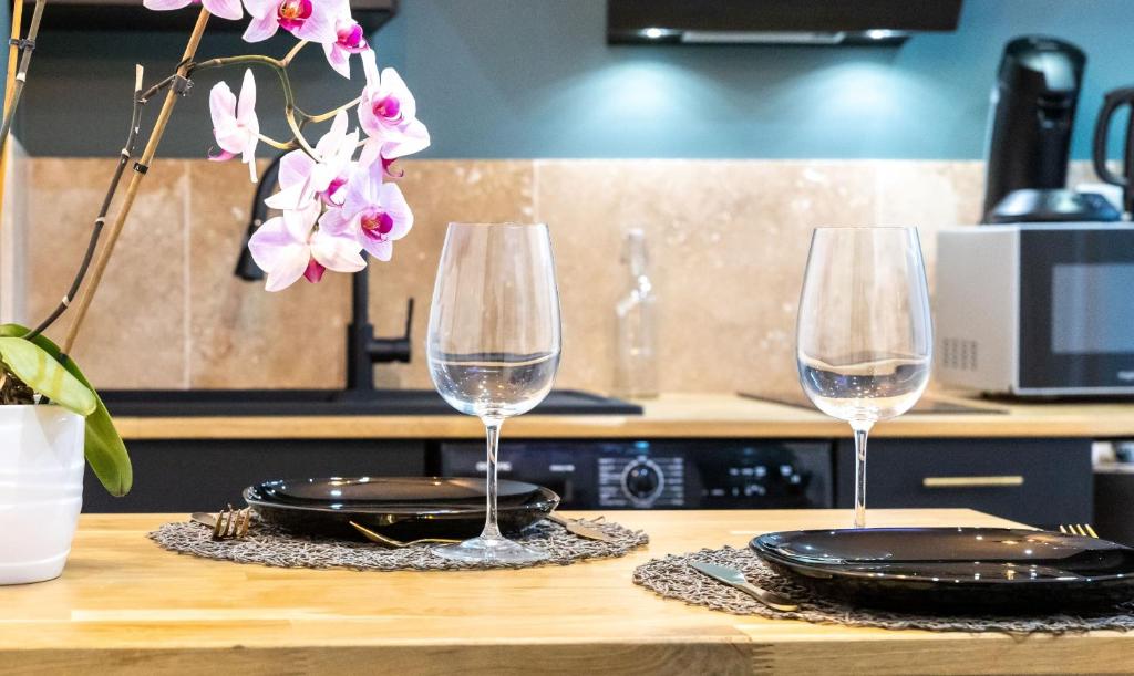 2 verres à vin assis au-dessus d'une table en bois dans l'établissement Le Cinq : Appartement Chic&Cosy, jardin privatif, à Vesoul