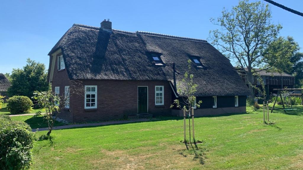 an old house with a thatched roof on a yard at Bed en Boomgaard in Giethoorn