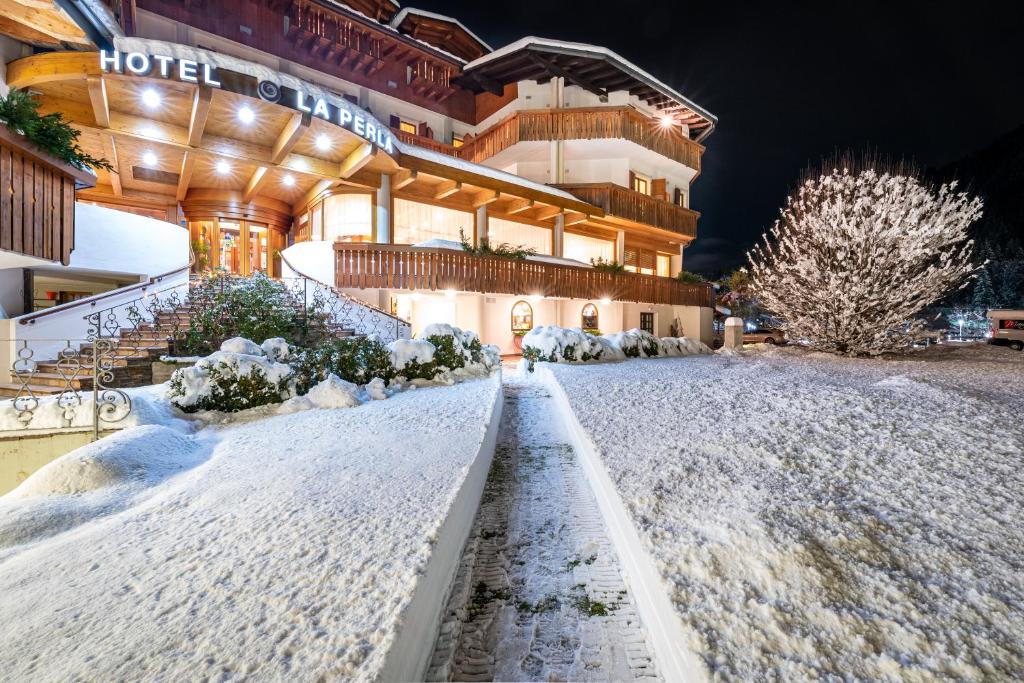 un hotel nella neve di notte di Hotel La Perla a Ravascletto