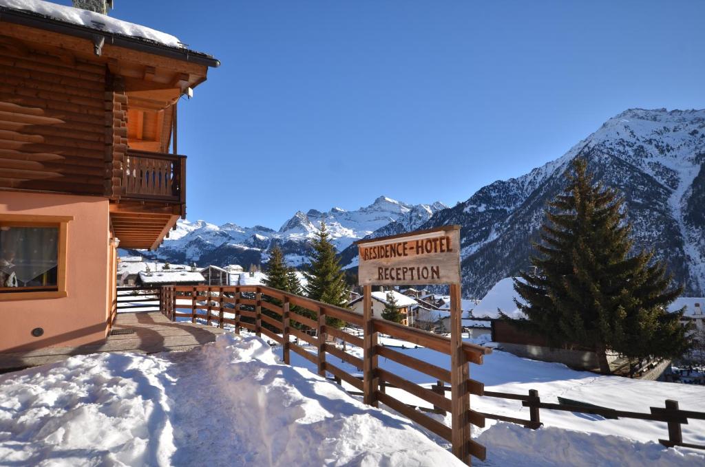 a sign in the snow next to a building at Hotel L'espoir in Champoluc