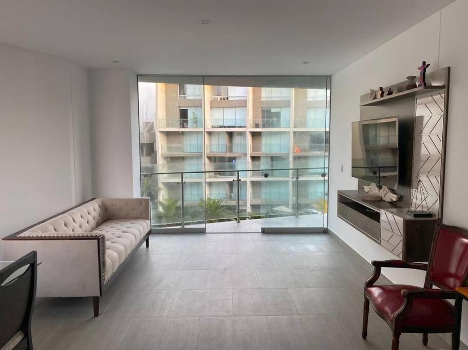 un soggiorno con divano e una grande finestra di Hermoso apartamento en Ocean Reef San Bartolo, con acceso piscina y área sociales! a San Bartolo