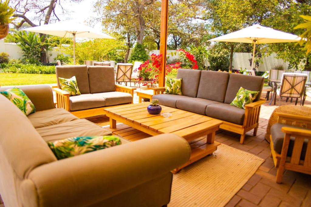 un patio con sofás, mesa de centro y sombrillas en Burley House by Ulendo, en Lilongwe