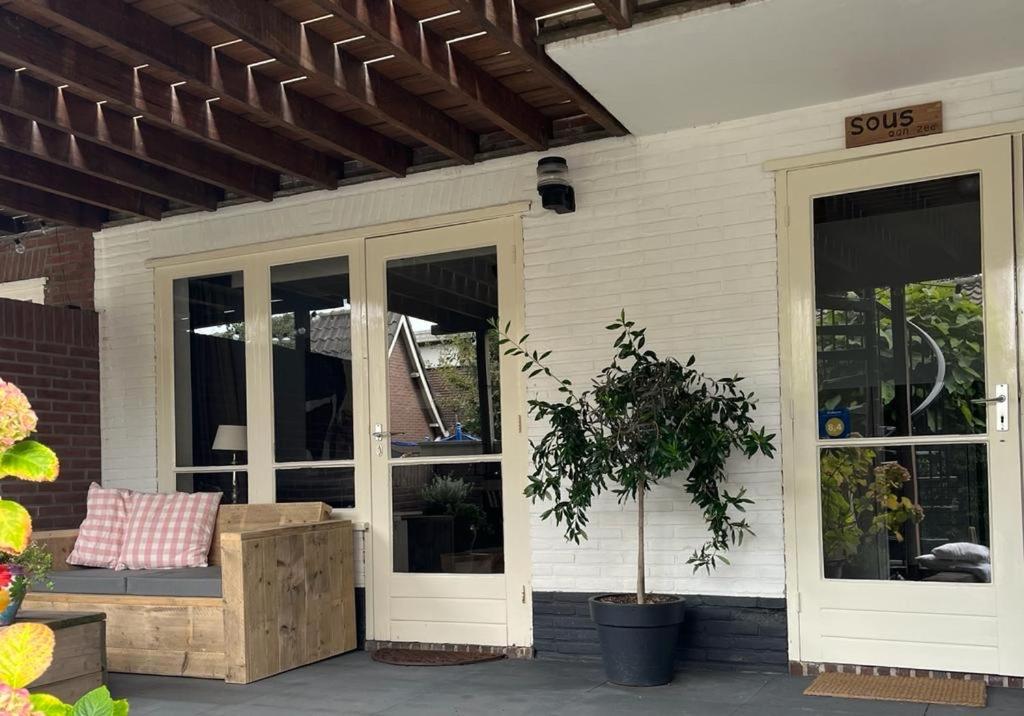 une terrasse couverte d'une maison avec un banc et des fenêtres dans l'établissement Sous aan Zee, à Noordwijk